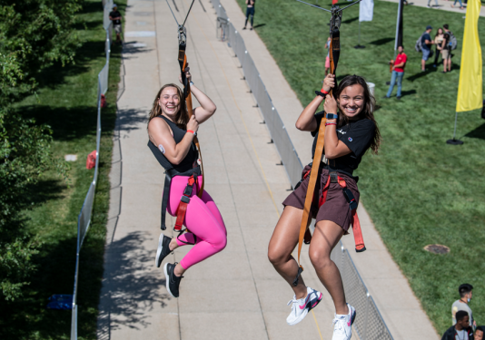 Two females smiling riding on a zipline