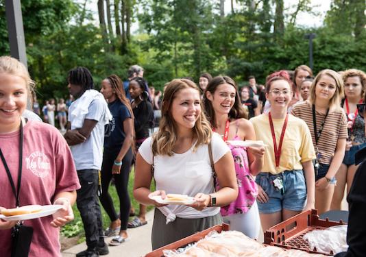 Smiling students standing in line for a meal at campus kickoff