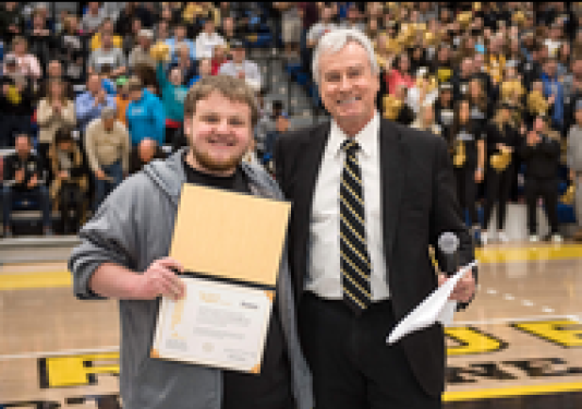 Noah Olson accepts One Brick Higher Award from Chancellor Elsenbaumer