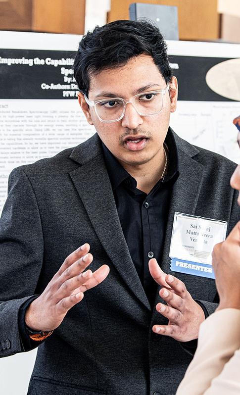 A student explains his research project to a judge at the symposium