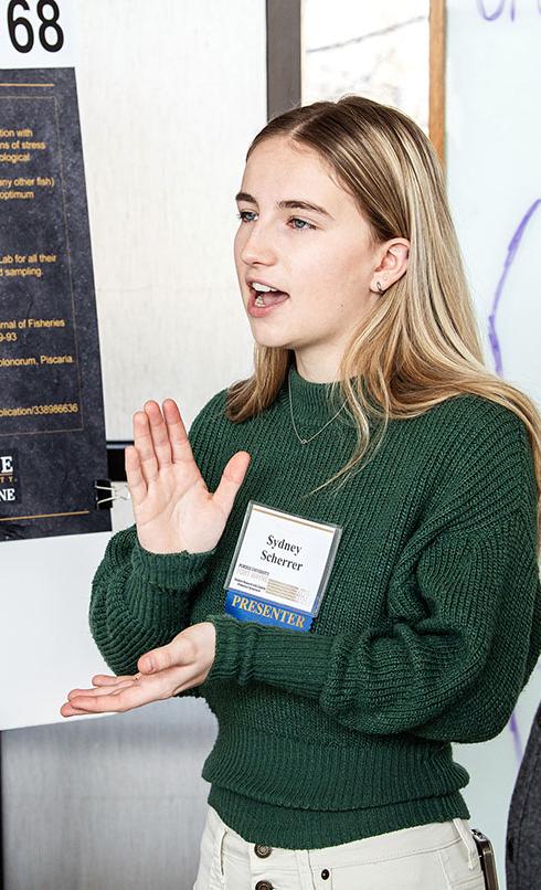 A student explains her research project to a judge at the symposium