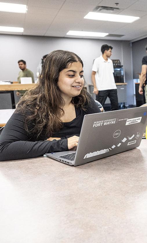 Two students are working at their computers and looking at each other