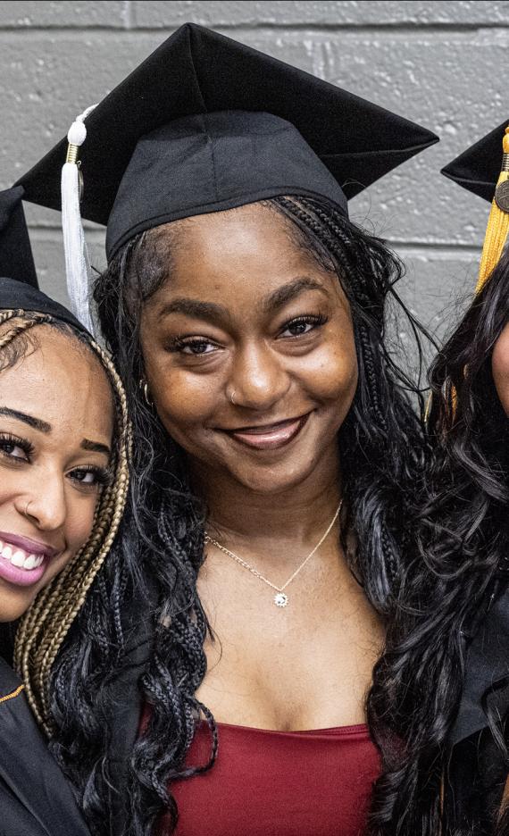 Three students pose at the 2026 commencement ceremony
