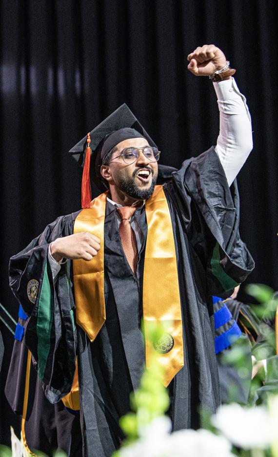 A student celebrates on the commencement stage