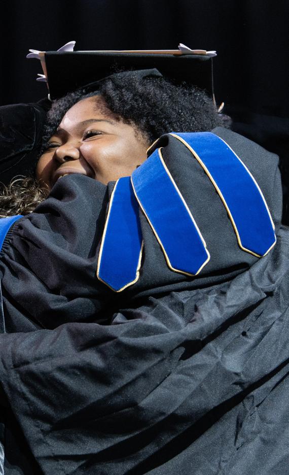 A student and faculty member embrace during the 2026 commencement ceremony
