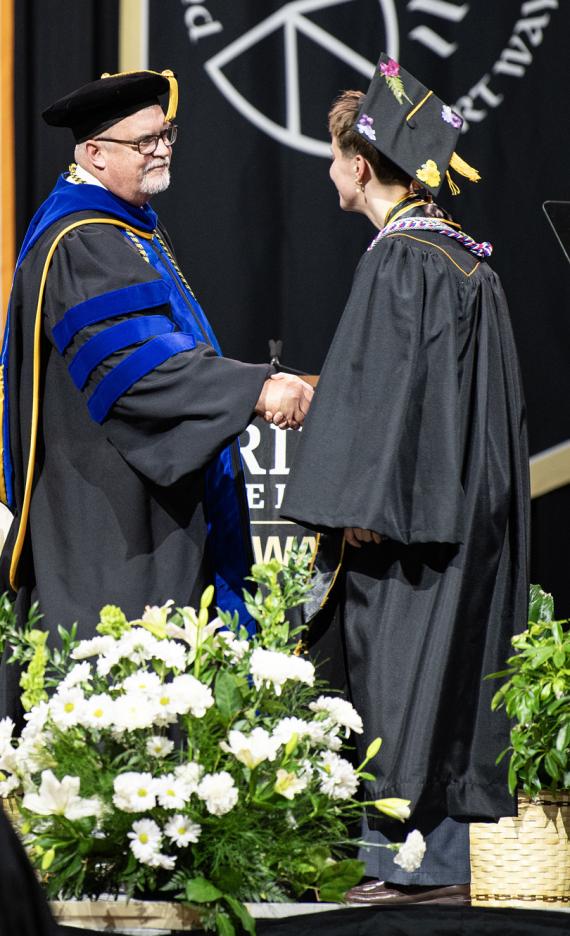 Vice chancellors congradulate a graduate at the 2026 commencement ceremony