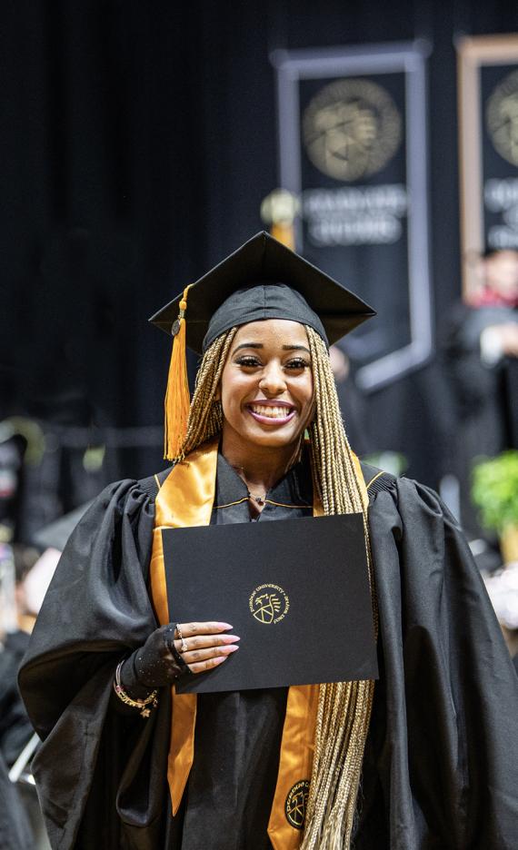 A female student poses with a degree at the 2026 commencement ceremony