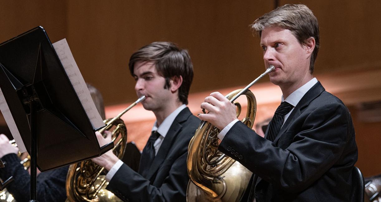 Two students are playing French hons in the Symphonic Wind Ensemble