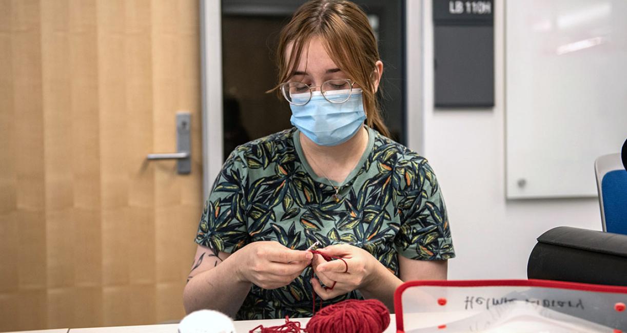 A person holds a crochet hook and yarn.