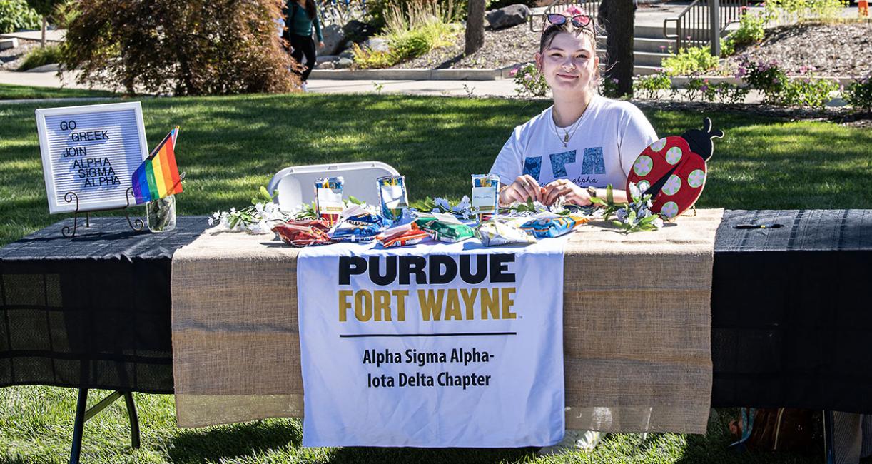 A member of Alpha Sigma Alpha is sitting at a table