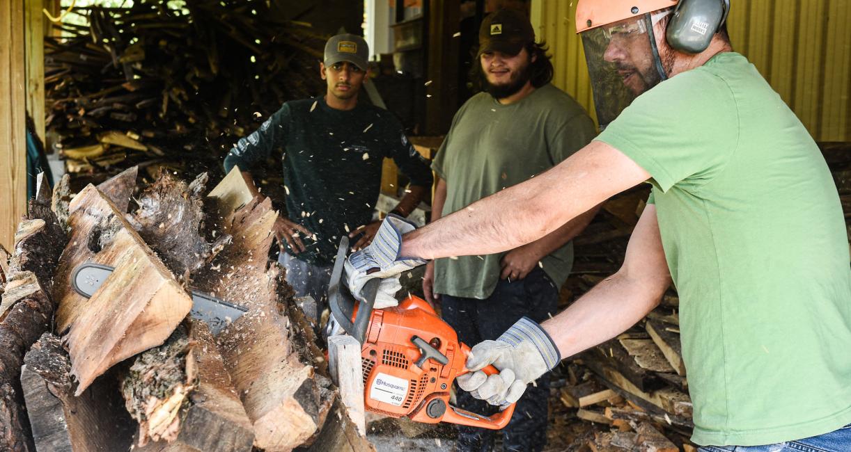 A man is cutting up wood with a chainsaw