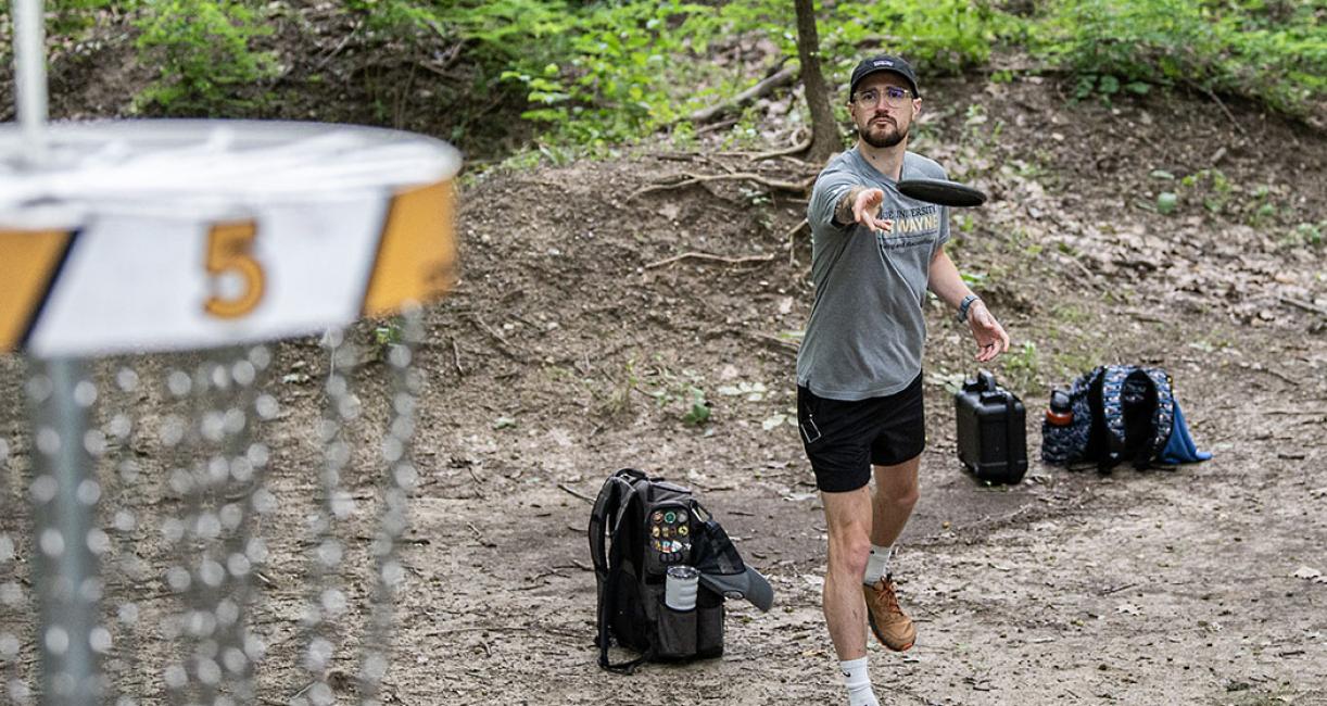 Nick Brand takes aim at a disc golf basket.