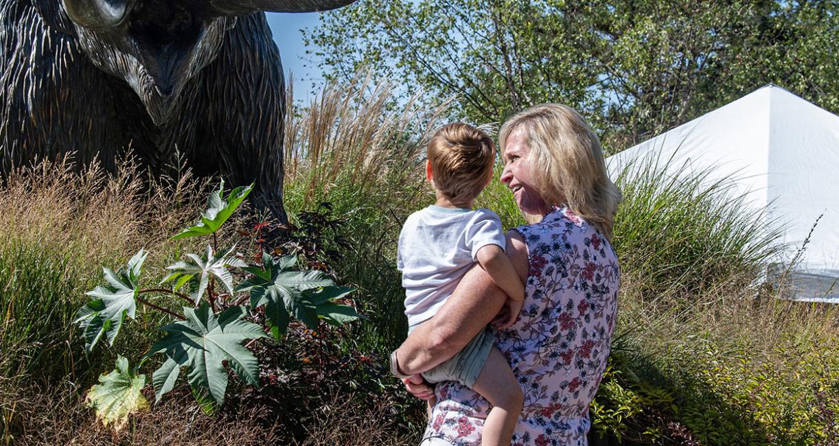 An employee and her child admire the bronze mastodon statue on the Alumni Plaza.