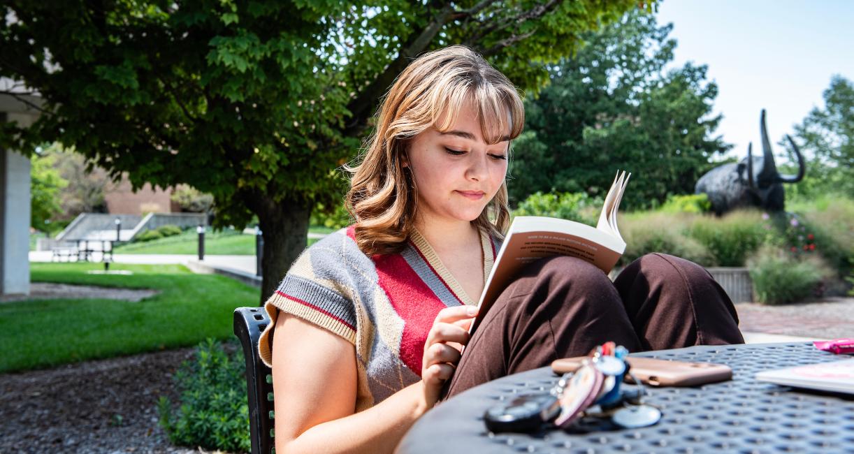 Student reading a book outside.