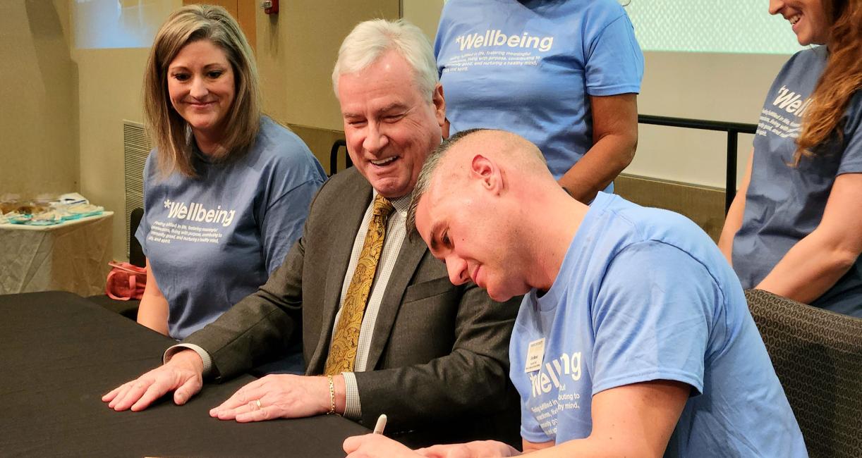 Eric Manor, associate chief of campus and community wellbeing, adds his signature to the charter.