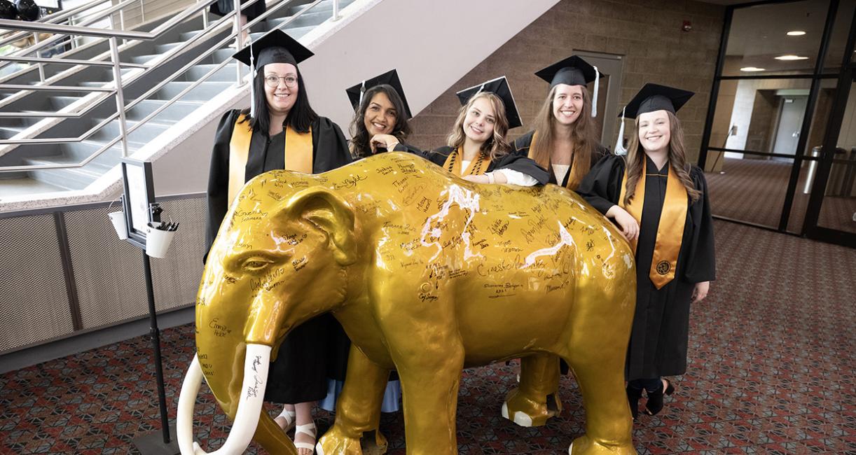 Graduates with a mastodon statue