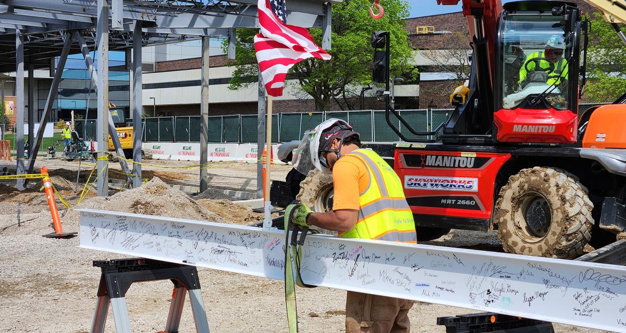 A construction worker readies the autographed beam before it is hoisted to the top of the building.