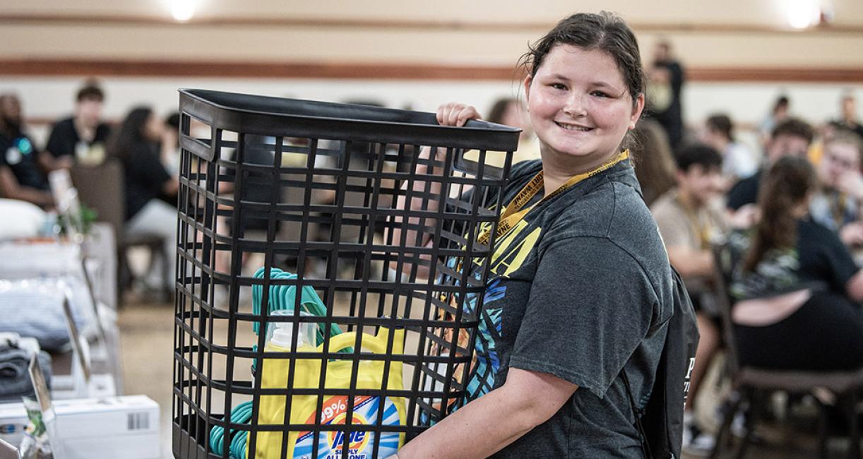 A new student is holding a laundry basket at NSO bingo night