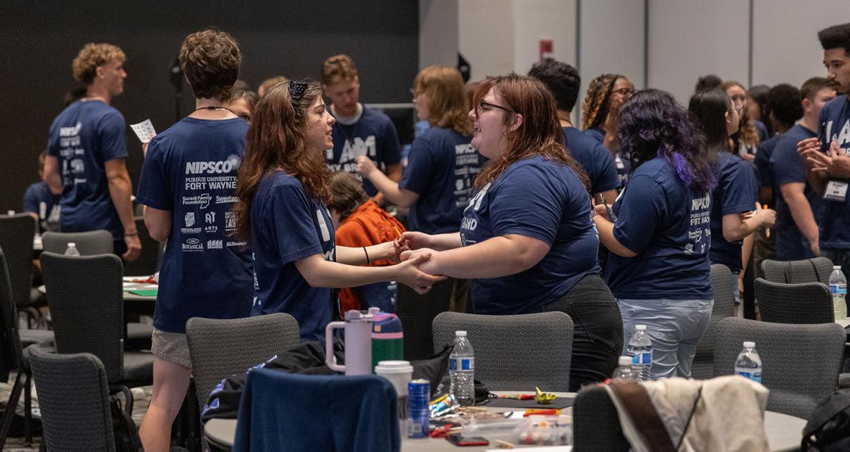 Two students are holding hands at a conference