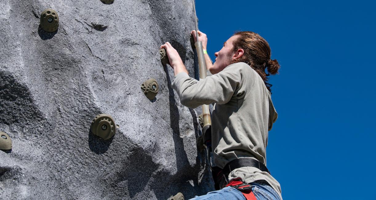 A student is climbing a rock wall