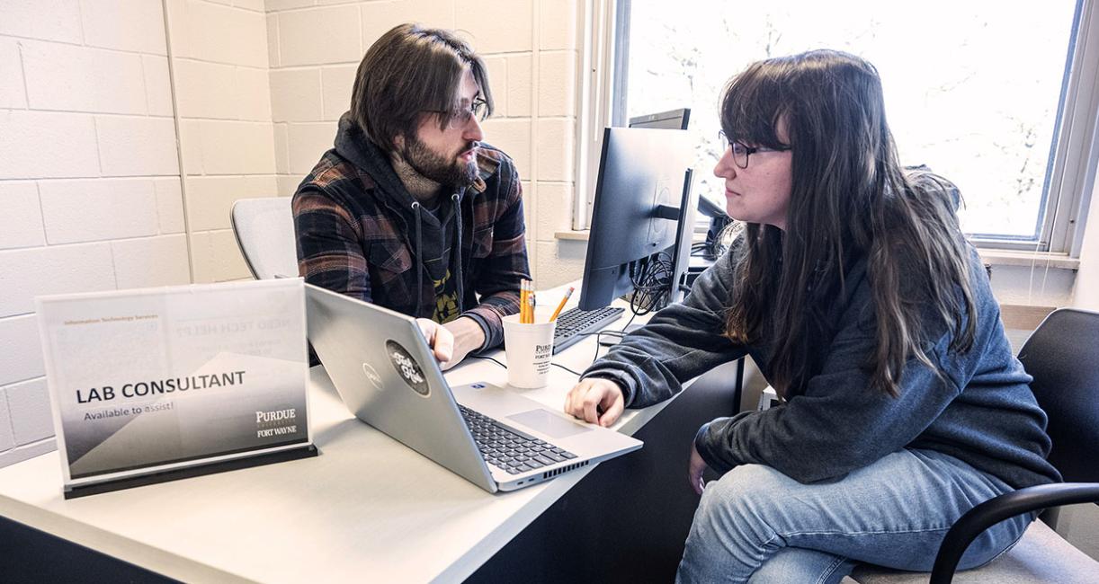 Two people at a service help desk in a computer lab