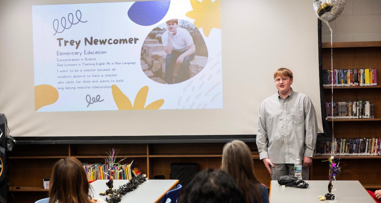 A student is standing in front of a screen in a classroom