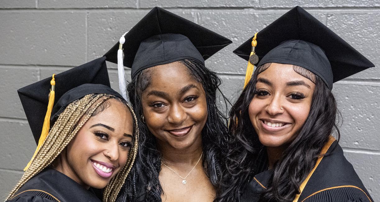Three students pose at the 2026 commencement ceremony