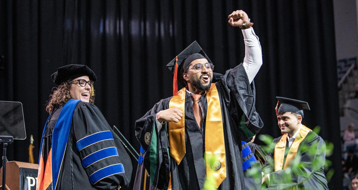 A student celebrates on the commencement stage