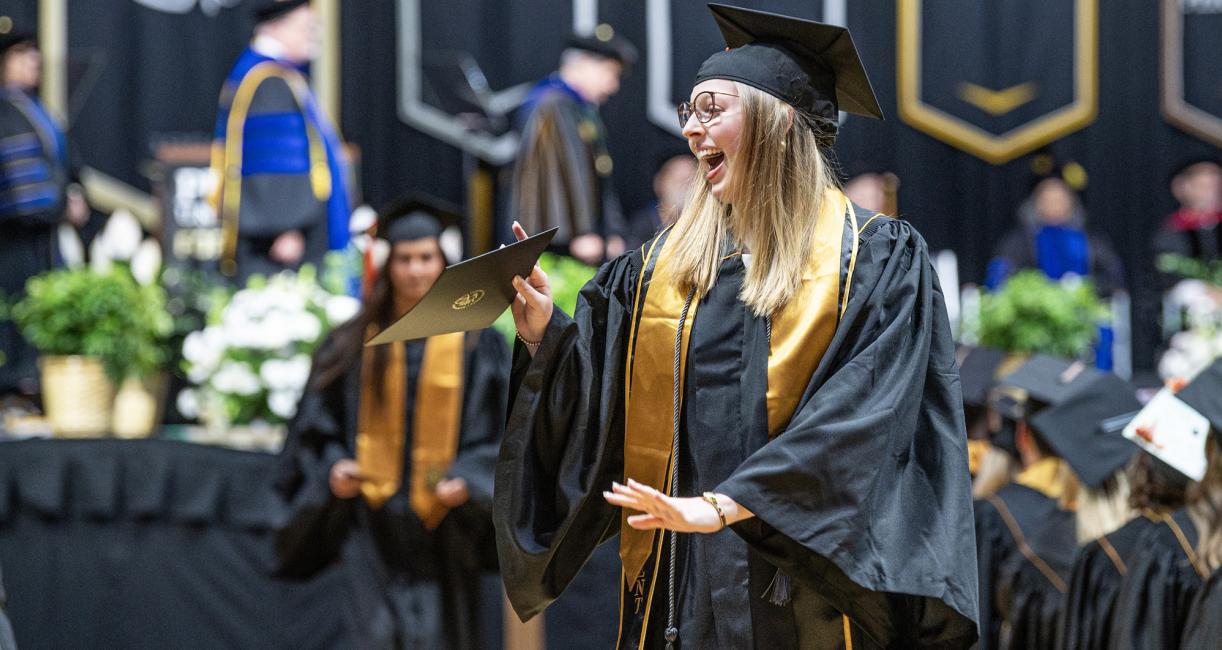 A female student walks down the aisle at the 2026 commencement ceremony