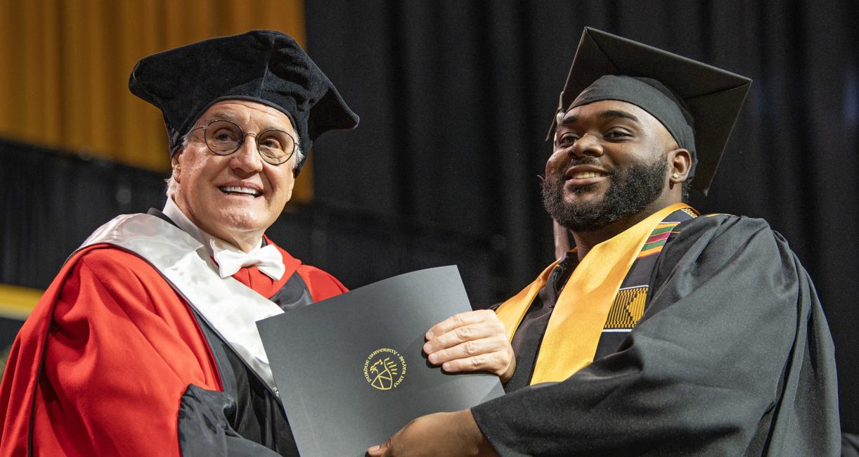 A student recieves a degree on the commencement stage
