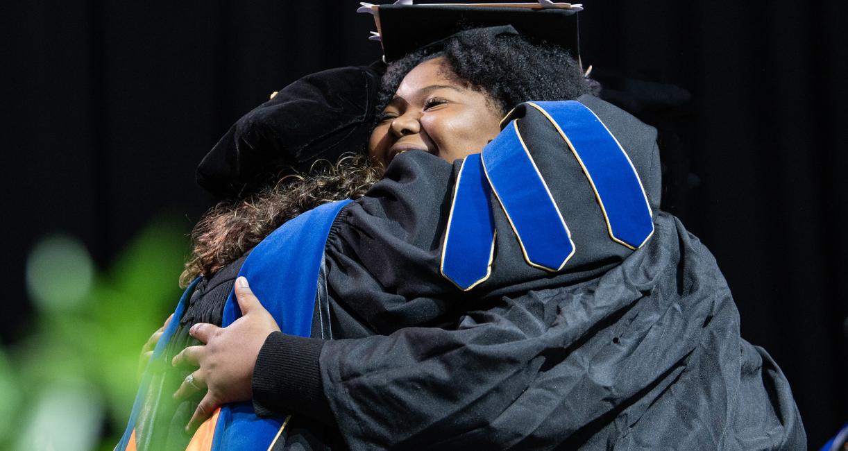 A student and faculty member embrace during the 2026 commencement ceremony