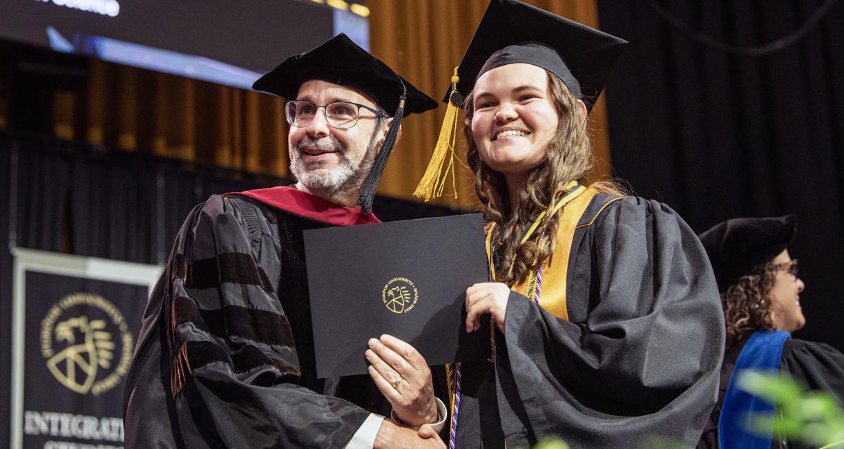 A student and dean shake hands during the 2026 commencement ceremony