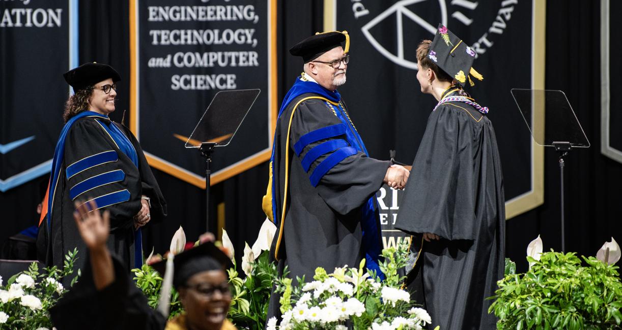 Vice chancellors congradulate a graduate at the 2026 commencement ceremony