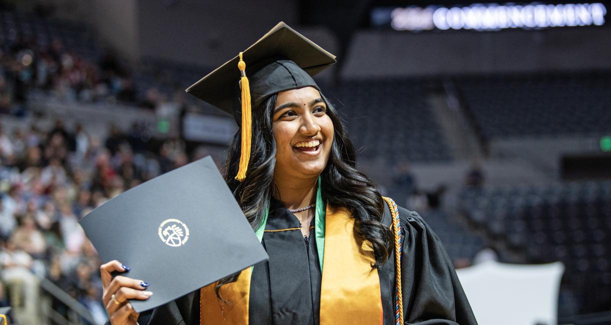 Female student poses with a degree at the 2026 commencement ceremony