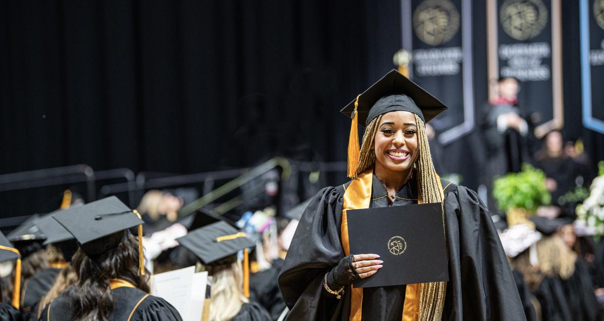 A female student poses with a degree at the 2026 commencement ceremony