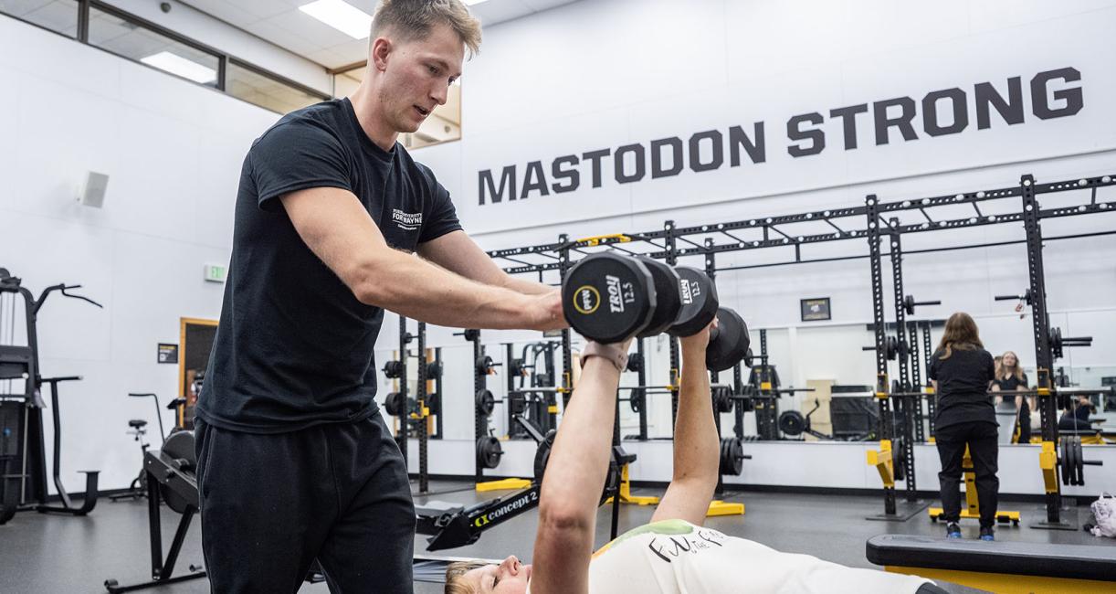 A trainer is assisting a person on a bench press